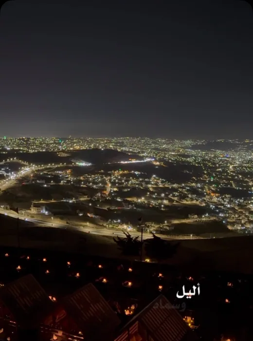 المكان من بعيد ليلاً وأضواء عمّان الممتدة خلفه